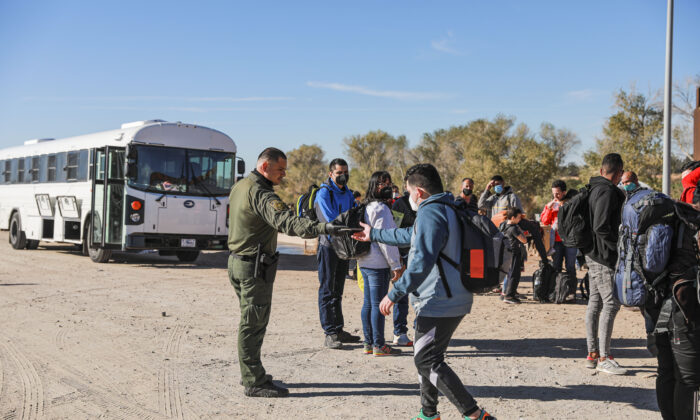 Un agente de la Patrulla Fronteriza organiza a los inmigrantes ilegales reunidos cerca de una valla fronteriza tras cruzar de México a Estados Unidos en Yuma, Arizona, el 10 de diciembre de 2021. (Charlotte Cuthbertson/The Epoch Times)
