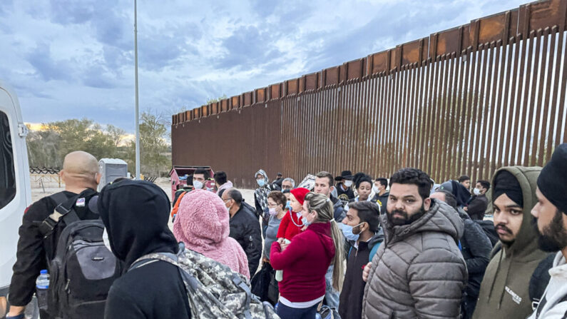 Inmigrantes ilegales se reúnen junto a la valla fronteriza después de cruzar de México a Estados Unidos en Yuma, Arizona, el 9 de diciembre de 2021. (Charlotte Cuthbertson/The Epoch Times)