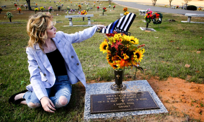 Danielle Collins, hija del oficial de policía asesinado William "Billy" Collins, ajusta una bandera en la tumba de su padre en Doyline, Luisiana, el 17 de noviembre de 2021. Dijo que visita su lápida en ocasiones, especialmente cuando tiene un "mal día". (Bobby Sánchez para The Epoch Times)