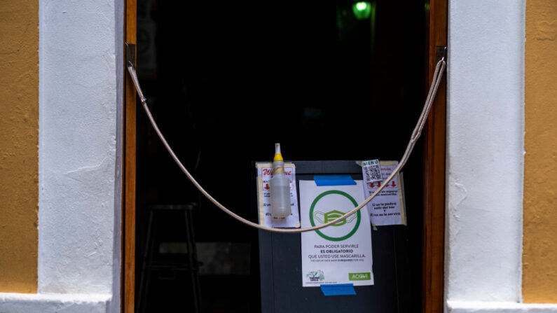 Un cartel que obliga a la gente a llevar mascarillas y una botella de desinfectante se ven en la entrada de un restaurante en el Viejo San Juan, Puerto Rico, el 20 de julio de 2020. (Ricardo Arduengo/AFP vía Getty Images)