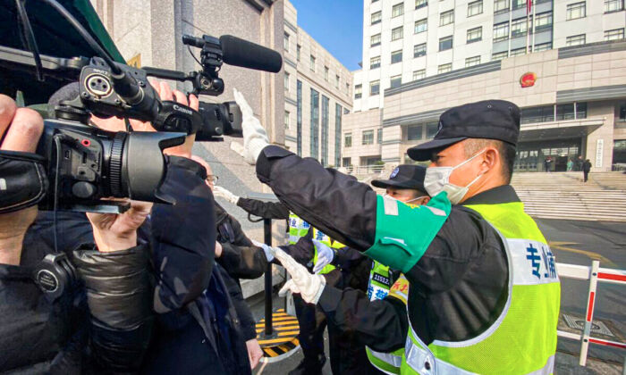 Un policía cubre una cámara para evitar que los periodistas graben imágenes frente al Tribunal Popular del Nuevo Distrito de Pudong de Shanghai, donde la periodista china de corte independiente, Zhang Zhan, será juzgada en Shanghai, el 28 de diciembre de 2020. (Leo Ramirez/AFP a través de Getty Images)