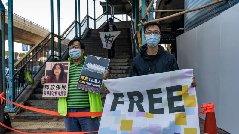 Activistas en favor de la democracia sostienen pancartas mientras muestran su apoyo a doce residentes de Hong Kong detenidos en la China continental y a la exabogada Zhang Zhan frente a la Oficina de Enlace del Gobierno Popular Central el 28 de diciembre de 2020 en Hong Kong, China. (Anthony Kwan/Getty Images)