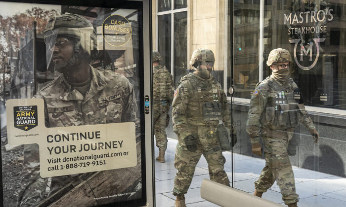 Tropas de la Guardia Nacional pasan por delante de un cartel de reclutamiento de la Guardia Nacional del Ejército en Washington, el 19 de enero de 2021. (Nathan Howard/Getty Images)