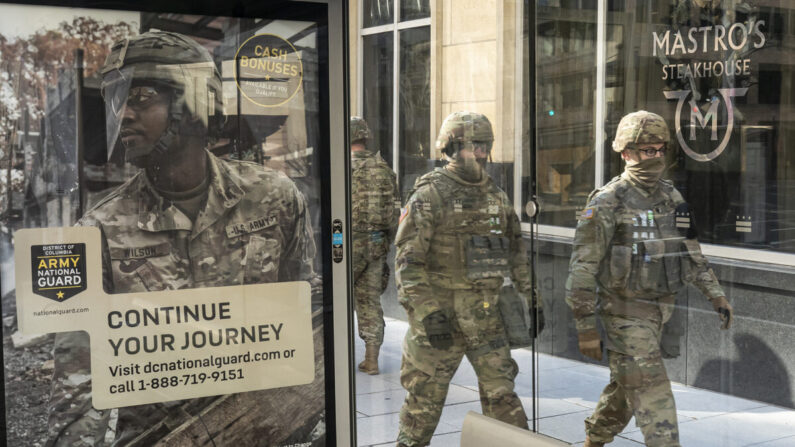 Tropas de la Guardia Nacional pasan por delante de un cartel de reclutamiento de la Guardia Nacional del Ejército en Washington, el 19 de enero de 2021. (Nathan Howard/Getty Images)