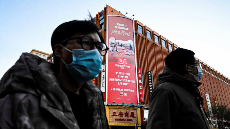 La gente pasa por delante de una valla publicitaria que promociona el "Día de los Solteros" anual del día 11, el mayor día de compras del año, en un complejo de centros comerciales en Beijing el 10 de noviembre de 2021. (Jade Gao/AFP vía Getty Images)