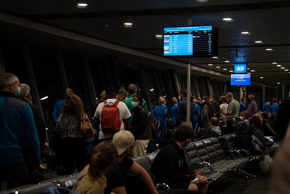 Pasajeros haciendo fila para embarcar en un vuelo con destino a Ámsterdam son observados en la terminal de salidas internacionales del Aeropuerto Internacional OR Tambo en Johannesburgo, el 27 de noviembre de 2021. (Foto de DIMITRI KORCZAK/AFP a través de Getty Images)