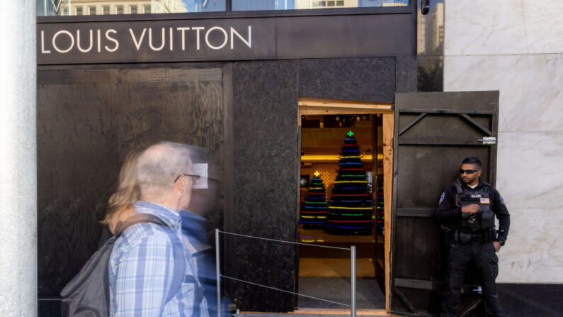 Un guardia de seguridad vigila la entrada de una tienda de Louis Vuitton, cuyos escaparates han sido recubiertos con tablas cerca de Union Square el 30 de noviembre de 2021 en San Francisco, California. (Ethan Swope/Getty Images)