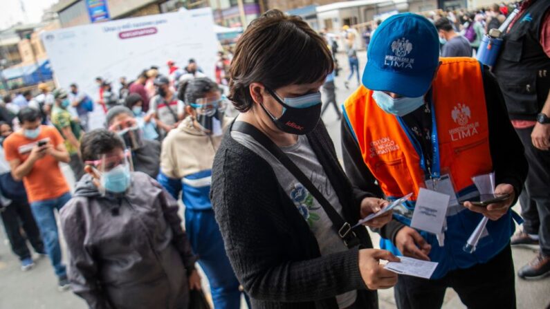 Personal de seguridad revisa los certificados de vacunación contra el covid-19 de las personas que ingresan a locales comerciales en el mercado Mesa Redonda de Lima (Perú), el 10 de diciembre de 2021. (Ernesto Benavides/AFP vía Getty Images)