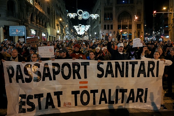 Manifestantes sostienen una pancarta en la que se lee "pasaporte sanitario, estado totalitario", durante una manifestación contra el pasaporte sanitario COVID-19, con el que las autoridades pretenden limitar la propagación de la pandemia del COVID-19, en Barcelona, el 11 de diciembre de 2021. (LLUIS GENE/AFP vía Getty Images)