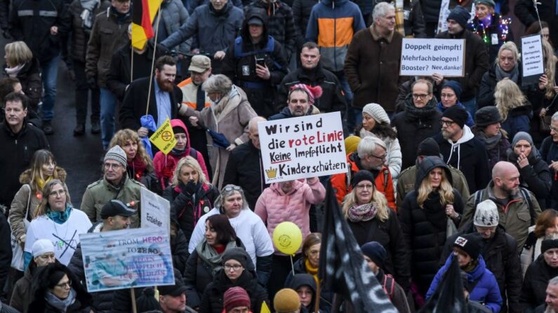 Manifestantes participan en una protesta y sostienen pancartas en las que se lee "Somos la línea roja, no a la vacunación obligatoria, protege a los niños" (c) y "¡Doblemente vacunado, mentido varias veces! ¿Vacunas de refuerzo? No gracias", contra las restricciones del Gobierno relacionadas con la pandemia del covid-19, en Dusseldorf, oeste de Alemania, el 18 de diciembre de 2021. (Ina Fassbender/AFP vía Getty Images)