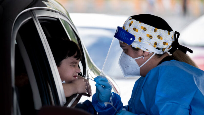 Una trabajadora de la salud realiza una prueba de covid-19 a un niño en un centro de pruebas de conducción operado por el Departamento de Salud de Puerto Rico en el estacionamiento del Estadio Hiram Bithorn, en San Juan, Puerto Rico, el 18 de diciembre de 2021. (Ricardo Arduengo/AFP vía Getty Images)