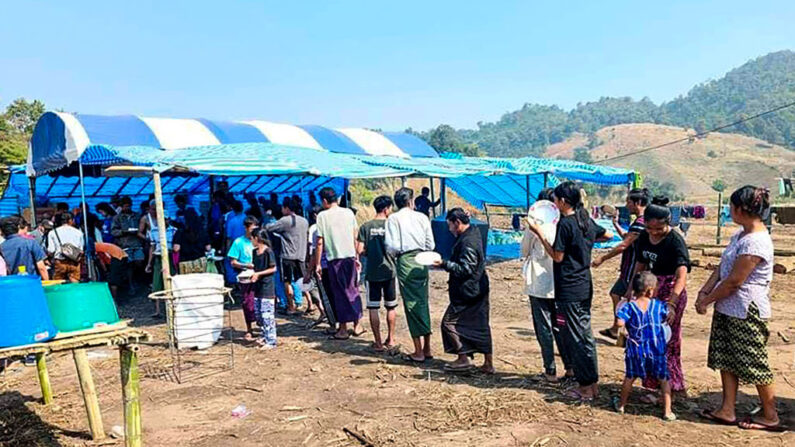 Personas que huyen debido a los combates entre el ejército y la Unión Nacional Karen (KNU) hacen cola para recibir alimentos en un alojamiento temporal para desplazados internos en el estado de Karen, a lo largo de la frontera entre Tailandia y Birmania, el 25 de diciembre de 2021. (STR/AFP vía Getty Images)