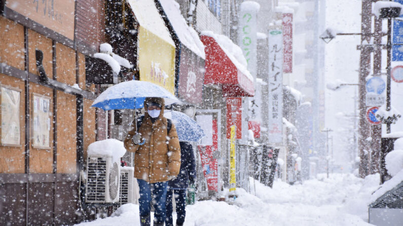 La gente camina por una calle bajo una fuerte nevada en la ciudad de Toyama, prefectura de Toyama (Japón), provocada por un frente frío extremo a lo largo del oeste y el norte del país el 27 de diciembre de 2021. (STR/JIJI PRESS/AFP vía Getty Images)