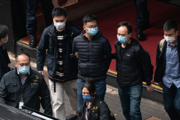 El editor jefe de Stand News, Patrick Lam, es introducido en un vehículo después de que la policía registrara las instalaciones de la oficina del medio de comunicación independiente en Hong Kong, el 29 de diciembre de 2021. (Anthony Kwan/Getty Images)