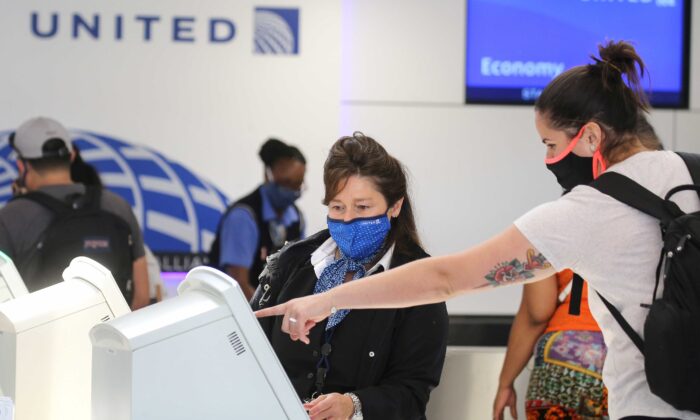 Una empleada de United Airlines con mascarilla de uso obligatorio atiende a un pasajero en el Aeropuerto Internacional de Los Ángeles (LAX) en medio de la pandemia de COVID-19, en Los Ángeles, California, el 1 de octubre de 2020. (Mario Tama/Getty Images)