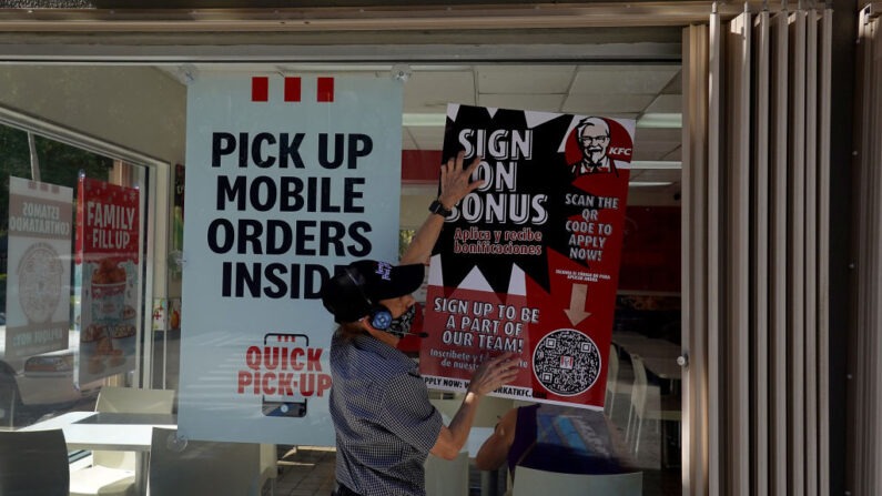 Una empleada de KFC coloca un cartel de bonificación por contratación en el restaurante el 03 de diciembre de 2021 en Miami, Florida. (Joe Raedle/Getty Images)