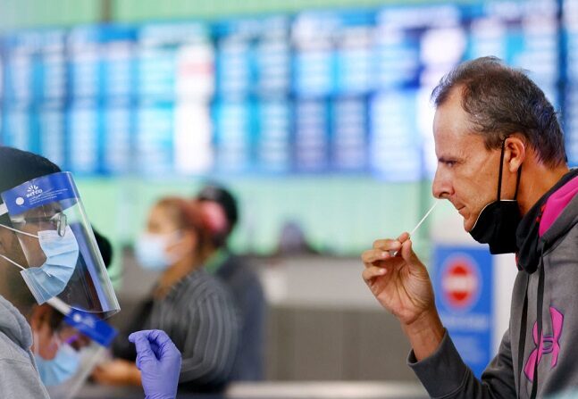Un pasajero que llegó de Italia se administra un hisopado nasal auto recogido en el primer día de un nuevo sitio de pruebas rápidas de COVID-19 para los pasajeros internacionales que llegan al Aeropuerto Internacional de Los Ángeles (LAX) el 3 de diciembre de 2021 en Los Ángeles, California. (Mario Tama/Getty Images)