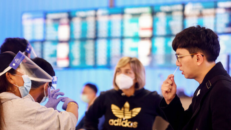 Un pasajero que llegó de Corea realiza un hisopado nasal en el primer día de un nuevo sitio de pruebas rápidas de COVID-19 para los pasajeros internacionales que llegan al Aeropuerto Internacional de Los Ángeles (LAX) el 3 de diciembre de 2021 en Los Ángeles, California. (Mario Tama/Getty Images)