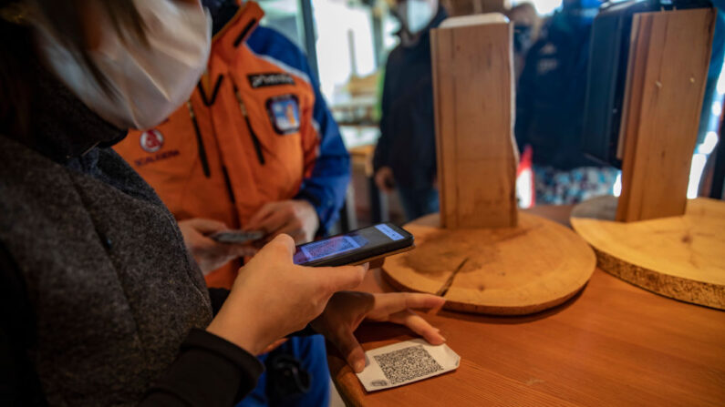 Unas personas comprueban su pase verde antes de entrar en un restaurante junto a las pistas de esquí el 12 de diciembre de 2021 en Obereggen, Italia. (Francesca Volpi/Getty Images)