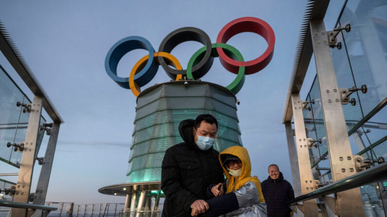 Visitantes caminan cerca de una columna con los Anillos Olímpicos mientras visitan el nivel superior de la Torre Olímpica en el Olympic Green cerca del Estadio Nacional, también conocido como Nido de Pájaro, el 11 de diciembre de 2021 en Beijing, China. (Kevin Frayer/Getty Images)