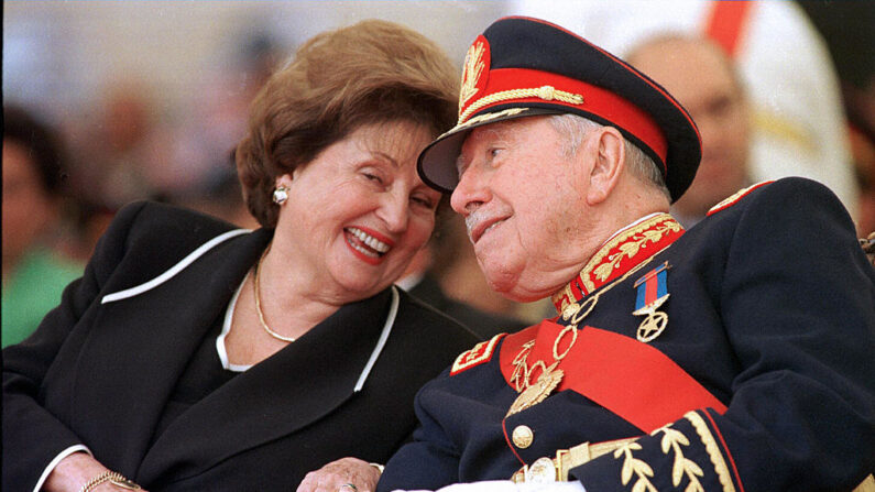 Fotografía tomada el 10 de marzo de 1998 del general Augusto Pinochet (d), escuchando a su esposa Lucía Hiriart durante la ceremonia de su retiro del mando del ejército en la Academia Militar de Santiago. (Cris Bouroncle/AFP vía Getty Images)