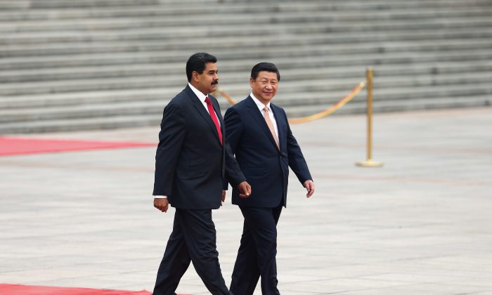 El líder chino Xi Jinping (Der.) acompaña al líder de Venezuela, Nicolás Maduro, a ver una guardia de honor durante una ceremonia de bienvenida frente al Gran Salón del Pueblo en Beijing el 22 de septiembre de 2013. (Lintao Zhang/Getty Images)