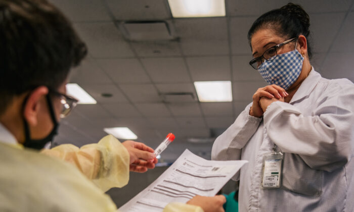 El asistente médico de Genview Diagnosis, Kenny Tran, devuelve a un técnico de laboratorio un test de COVID-19 en Foxconn Assembly en Houston, Texas, el 13 de agosto de 2021. (Brandon Bell/Getty Images)