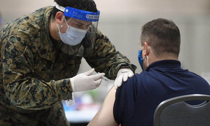 Un miembro de las Fuerzas Armadas de Estados Unidos administra una vacuna COVID-19 a un policía en un centro de vacunación comunitario de FEMA en Filadelfia, Pensilvania, el 2 de marzo de 2021. (Mark Makela/Getty Images)
