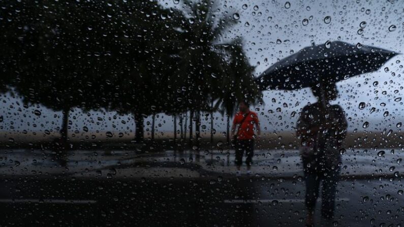 Unas personas se protegen de la lluvia en Río de Janeiro (Brasil), en una fotografía de archivo. EFE/Marcelo Sayão