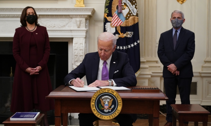 El presidente Joe Biden firma órdenes ejecutivas como parte de la respuesta al COVID-19 ante la presencia de la vicepresidenta Kamala Harris (iz.) y el director del NIAID Anthony Fauci en el Comedor de Estado de la Casa Blanca, en Washington, el 21 de enero de 2021. (Mandel Ngan/AFP vía Getty Images)