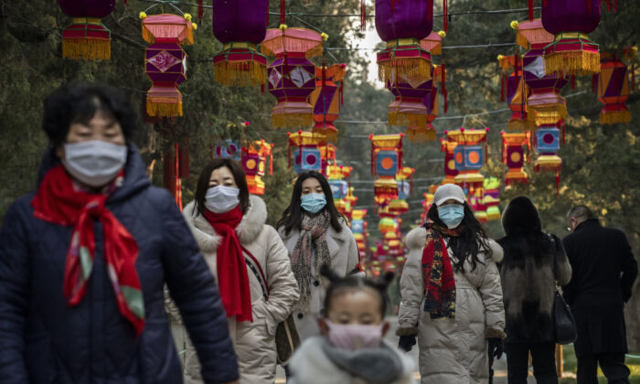 Residentes usan máscaras protectoras mientras caminan bajo las decoraciones del Año Nuevo chino, en un parque en Beijing, China, el 25 de enero de 2020. (Kevin Frayer/Getty Images)
