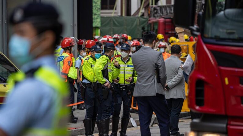Policías y bomberos frente al edificio del World Trade Centre en Causeway Bay, Hong Kong, China, 15 de diciembre de 2021. Alrededor de 1200 personas fueron evacuadas del edificio tras un incendio eléctrico que causó al menos 13 heridos, mientras que cientos seguían atrapados en la azotea. EFE/EPA/Jerome Favre