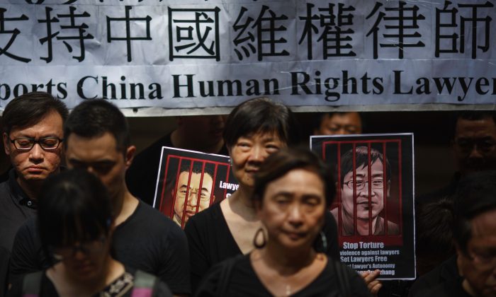 Retratos de los abogados chinos de derechos humanos detenidos Jian Tianyong ( Izq.) y Wang Quanzhang se ven mientras los activistas prodemocráticos de Hong Kong observan una protesta silenciosa en apoyo a los abogados de derechos humanos en China, frente al Tribunal de Apelación Final en el distrito central de Hong Kong el 9 de julio de 2017. (Tengku Bahar/AFP/Getty Images)
