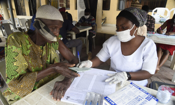 Asistente de salud entrega una tarjeta de vacunación COVID-19 en Lagos, Nigeria, el 26 de noviembre de 2021. (Pius Utomi Ekpei/AFP vía Getty Images)