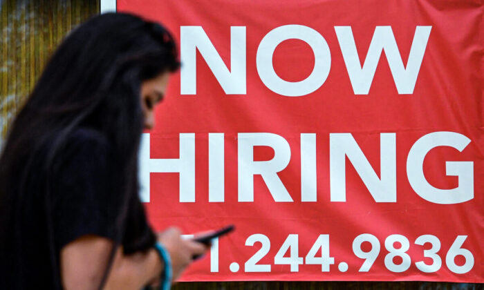 Una mujer pasa junto a un letrero que dice "Ahora Contratando" afuera de una tienda en Arlington, Virginia, el 16 de agosto de 2021. (Olivier Douliery/AFP a través de Getty Images)

