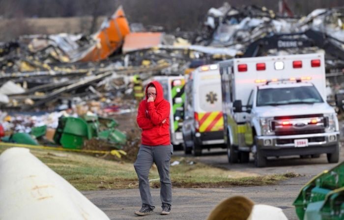 Una mujer se aleja de una fila de ambulancias en la propiedad de la fábrica de velas Mayfield Consumer Products después de que fuera destruida por un tornado, en Mayfield, Kentucky, el 11 de diciembre de 2021. (JOHN AMIS/AFP vía Getty Images)