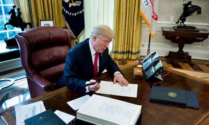 El presidente Donald Trump firma el proyecto de Ley de Empleos y Reducción de Impuestos en el Despacho Oval de la Casa Blanca en Washington, el 22 de diciembre de 2017. (Brendan Smialowski/AFP/Getty Images)