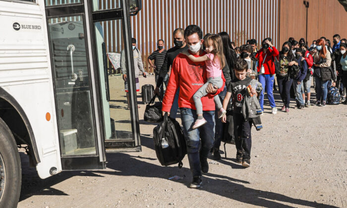 Los inmigrantes ilegales que se reunieron junto al muro fronterizo se preparan para subir a un autobús que se dirige a la estación de la Patrulla Fronteriza para su procesamiento en Yuma, Arizona, el 10 de diciembre de 2021. (Charlotte Cuthbertson/The Epoch Times)