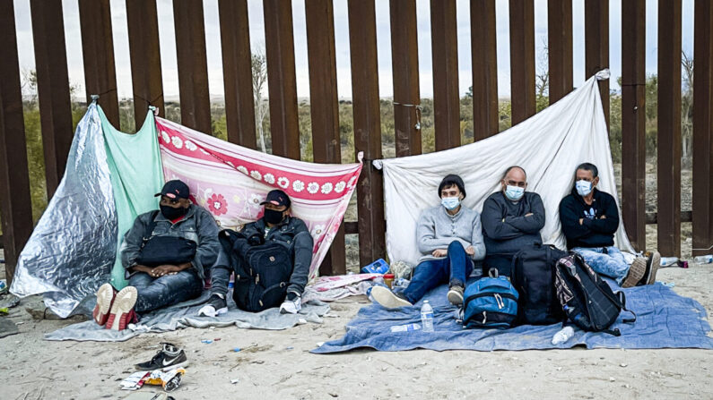 Inmigrantes ilegales esperan a la Patrulla Fronteriza junto a la valla fronteriza luego de cruzar la frontera entre Estados Unidos y México en Yuma, Arizona, el 9 de diciembre de 2021. (Charlotte Cuthbertson/The Epoch Times)