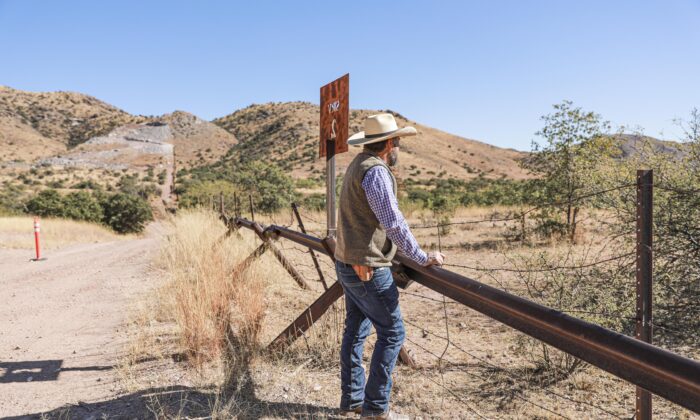 El detective Jake Kartchner, de la unidad fronteriza de la Oficina del Sheriff del condado de Cochise, se encuentra en la valla fronteriza entre Estados Unidos y México que se tenía previsto ser reemplazada por una valla de 30 pies antes de que el presidente Joe Biden detuviera toda la construcción del muro fronterizo en enero de 2021, en el condado de Cochise, Arizona, el 6 de diciembre de 2021. (Charlotte Cuthbertson/The Epoch Times)