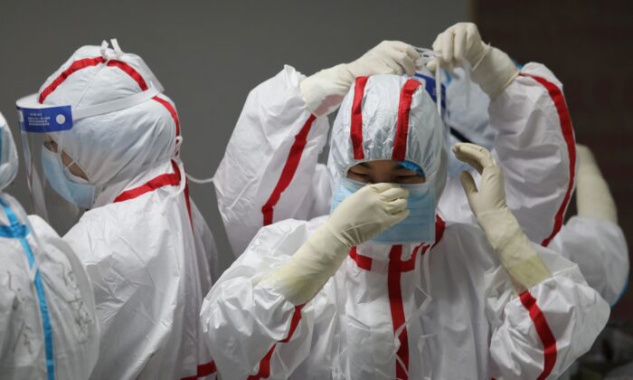 Personal médico se coloca equipo de protección antes de atender a pacientes con COVID-19, en el Hospital de la Cruz Roja, en Wuhan, China, el 16 de marzo de 2020. (STR/AFP vía Getty Images)
