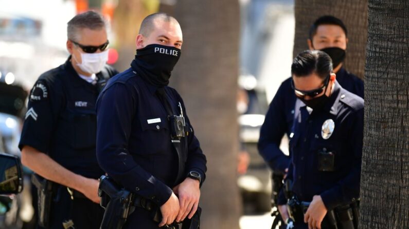 Agentes del Departamento de Policía de Los Ángeles (LAPD) llevan el rostro cubierto mientras vigilan una manifestación en el centro de Los Ángeles (EE.UU.), el 22 de abril de 2020. (Frederic J. Brown/AFP vía Getty Images)