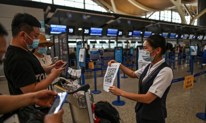 Pasajeros con mascarillas comprueban su código de salud con una hoja que sostiene un personal del aeropuerto (Der.) antes de la zona del ventanilla siguiendo los procedimientos preventivos contra la propagación del coronavirus COVID-19 en el Aeropuerto Internacional de Pudong en Shanghái, el 11 de junio de 2020. (Hector Retamal/AFP a través de Getty Images)