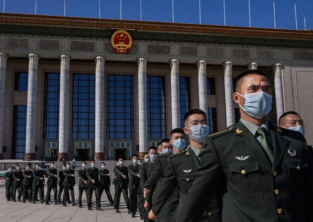 Soldados chinos del Ejército Popular de Liberación llevan mascarillas mientras marchan después de una ceremonia que marca el 70º aniversario de la entrada de China en la Guerra de Corea, el 23 de octubre de 2020 en el Gran Salón del Pueblo en Beijing, China. (Kevin Frayer/Getty Images)