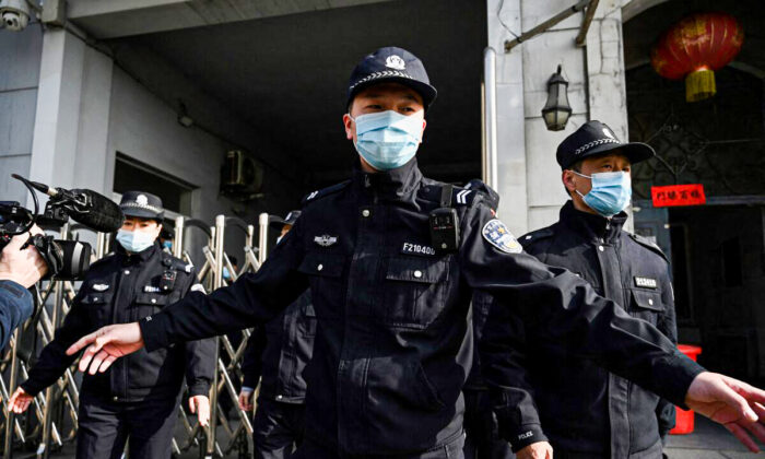 Policías aseguran una entrada lateral luego de la llegada de vehículos policiales al Tribunal Popular Intermedio de Dandong en la provincia de Liaoning, al noreste de China, el 19 de marzo de 2021 (Noel Celis / AFP a través de Getty Images).