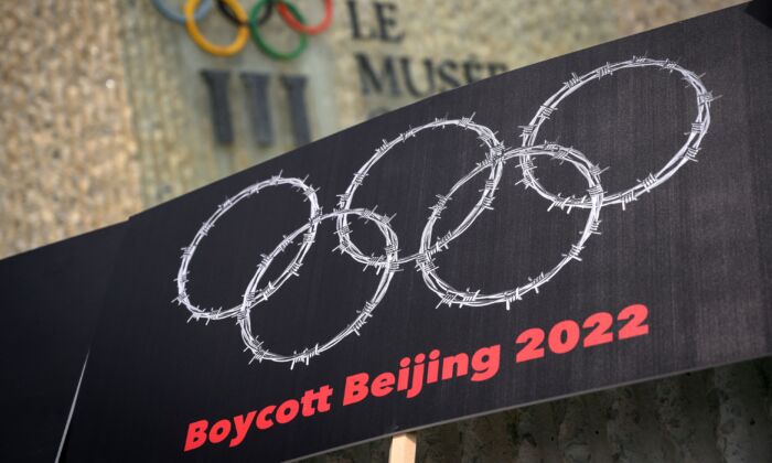 Pancarta con alambres de espino en forma de anillos olímpicos se ve junto a un cartel del Museo Olímpico durante una protesta organizada por activistas tibetanos y uigures contra los Juegos Olímpicos de Invierno de Beijing 2022, en Lausana, Suiza, el 23 de junio de 2021. (Fabrice Coffrini/AFP vía Getty Images)