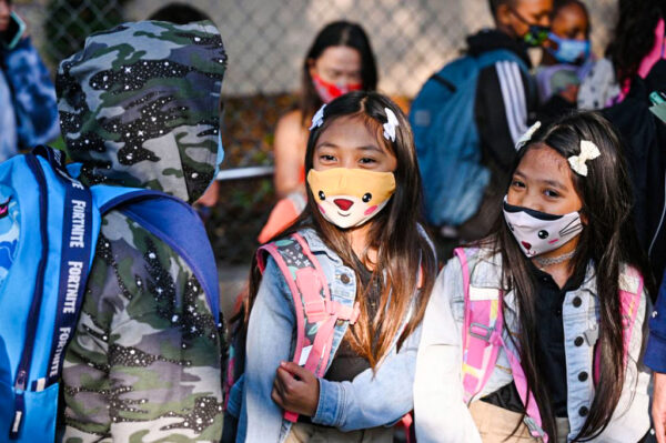 Estudiantes y padres llegan con mascarillas en el primer día del año escolar a la Escuela Primaria Grant, en Los Ángeles, el 16 de agosto de 2021. (Robyn Beck/AFP a través de Getty Images)