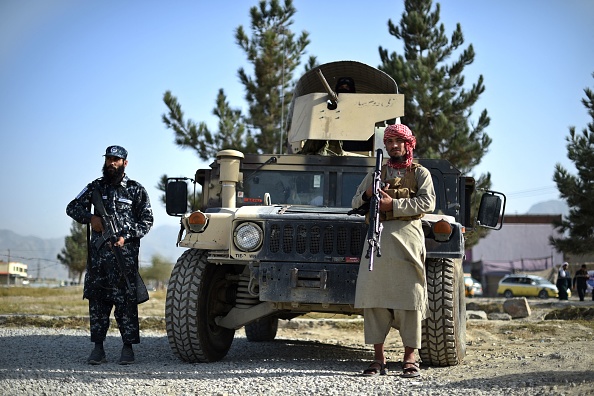En esta foto tomada el 3 de octubre de 2021, combatientes talibanes que fungen como fuerza policial hacen guardia junto a un vehículo Humvee en la puerta de entrada de un distrito policial en Kabul. (Foto de WAKIL KOHSAR/AFP a través de Getty Images)