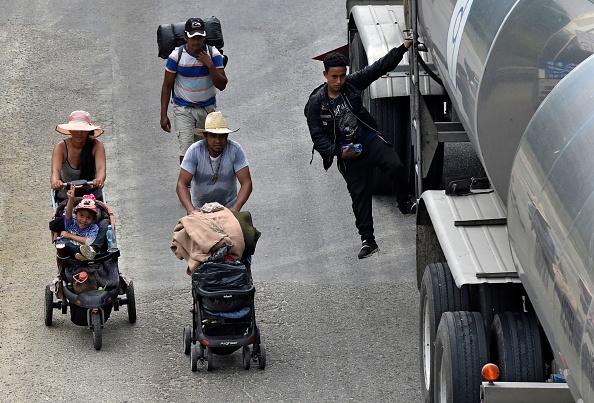 Inmigrantes que se dirigen en caravana hacia Estados Unidos, empujan carritos mientras caminan junto a otro inmigrante que cuelga de un camión en El Arenal, municipio de Sayula de Alemán, estado de Veracruz, México, el 18 de noviembre de 2021. (Foto de CLAUDIO CRUZ/AFP a través de Getty Images)
