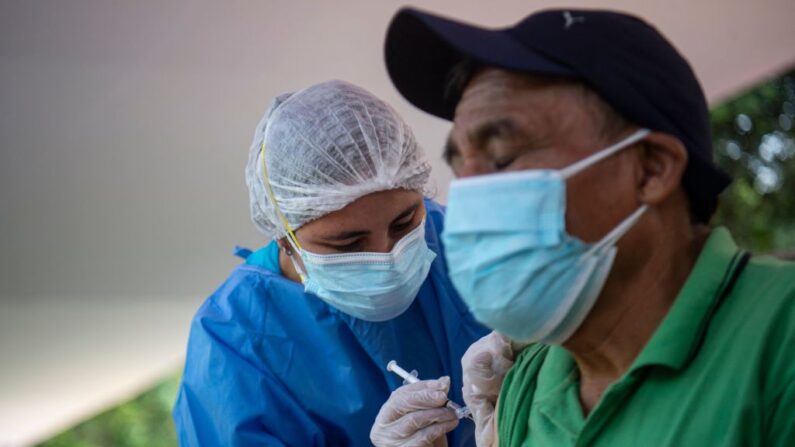 Una enfermera inocula a un hombre con la vacuna de Pfizer-BioNTech contra la enfermedad del COVID-19 en un centro de salud situado en la calle en Lima (Perú), el 11 de enero de 2022. (Ernesto Benavides/AFP vía Getty Images)